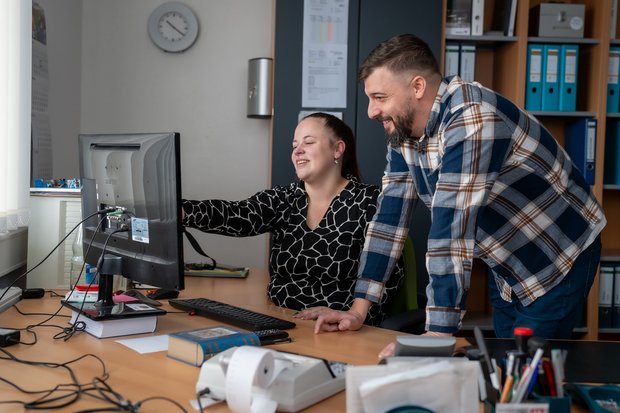 Zwei Mitarbeiter besprechen Inhalte auf einem Computer im Büro.